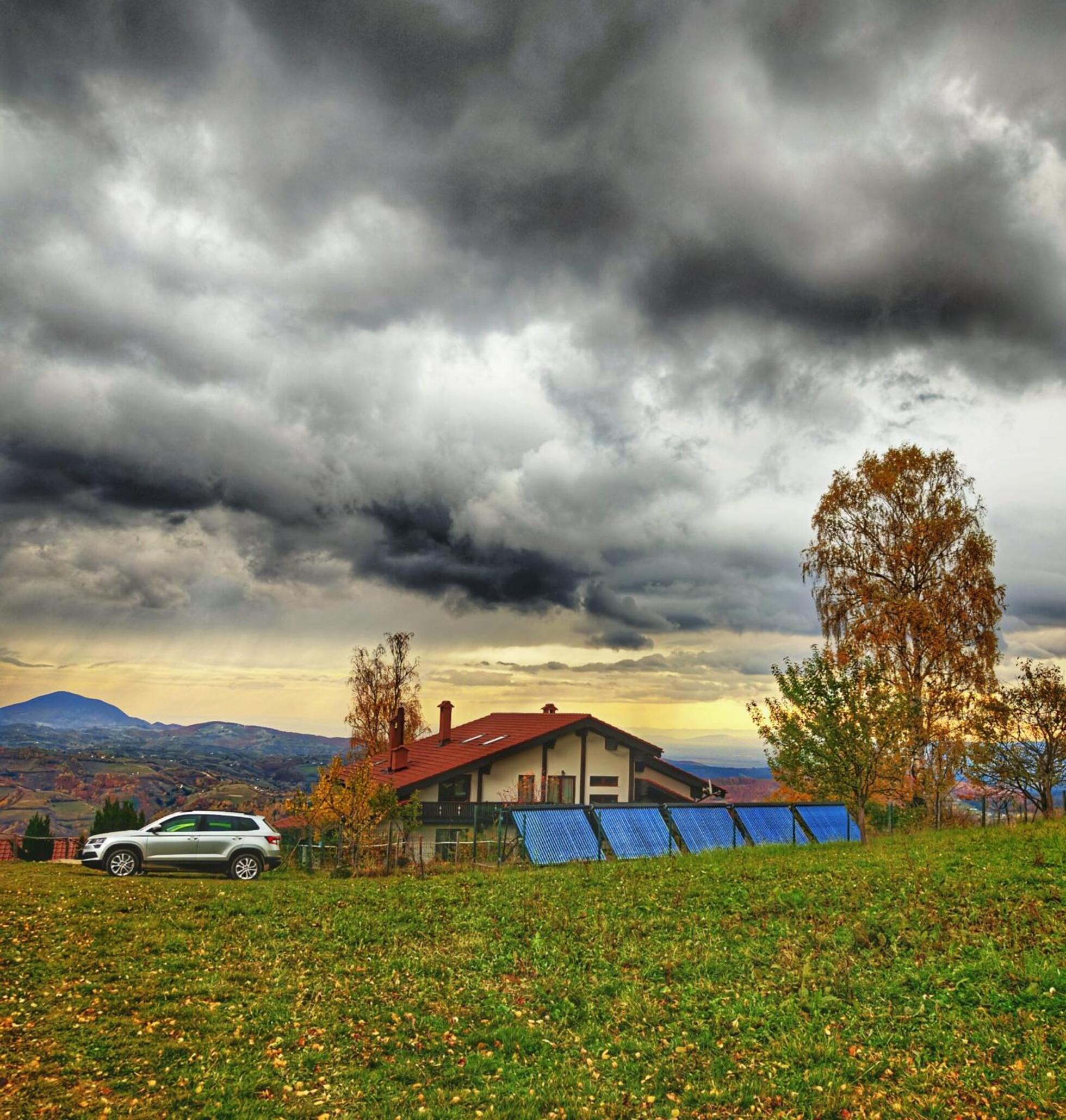 Casa La Vârf cu panoramă spre munți și nori dramatici